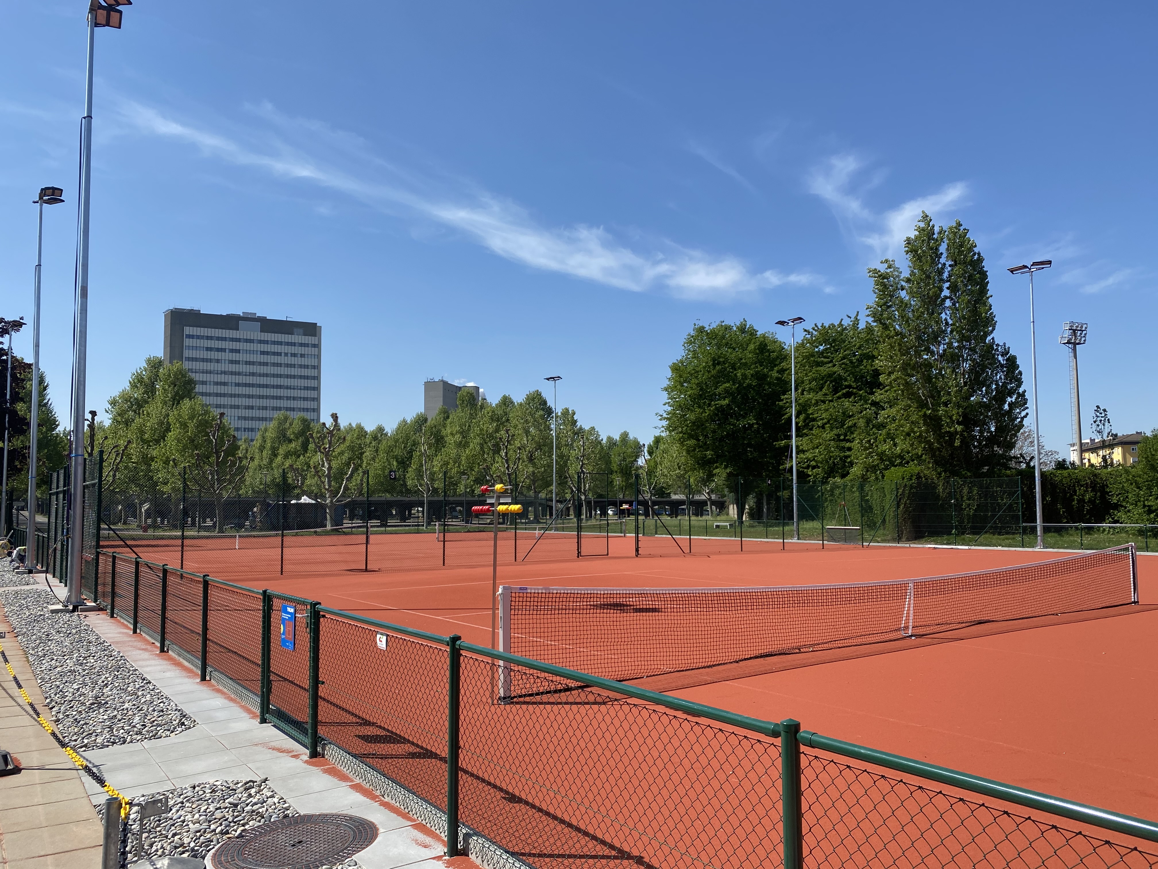 Bild des Tennisaussenplatzes des TC Novartis mit Novartis-Gebäude im Hintergrund